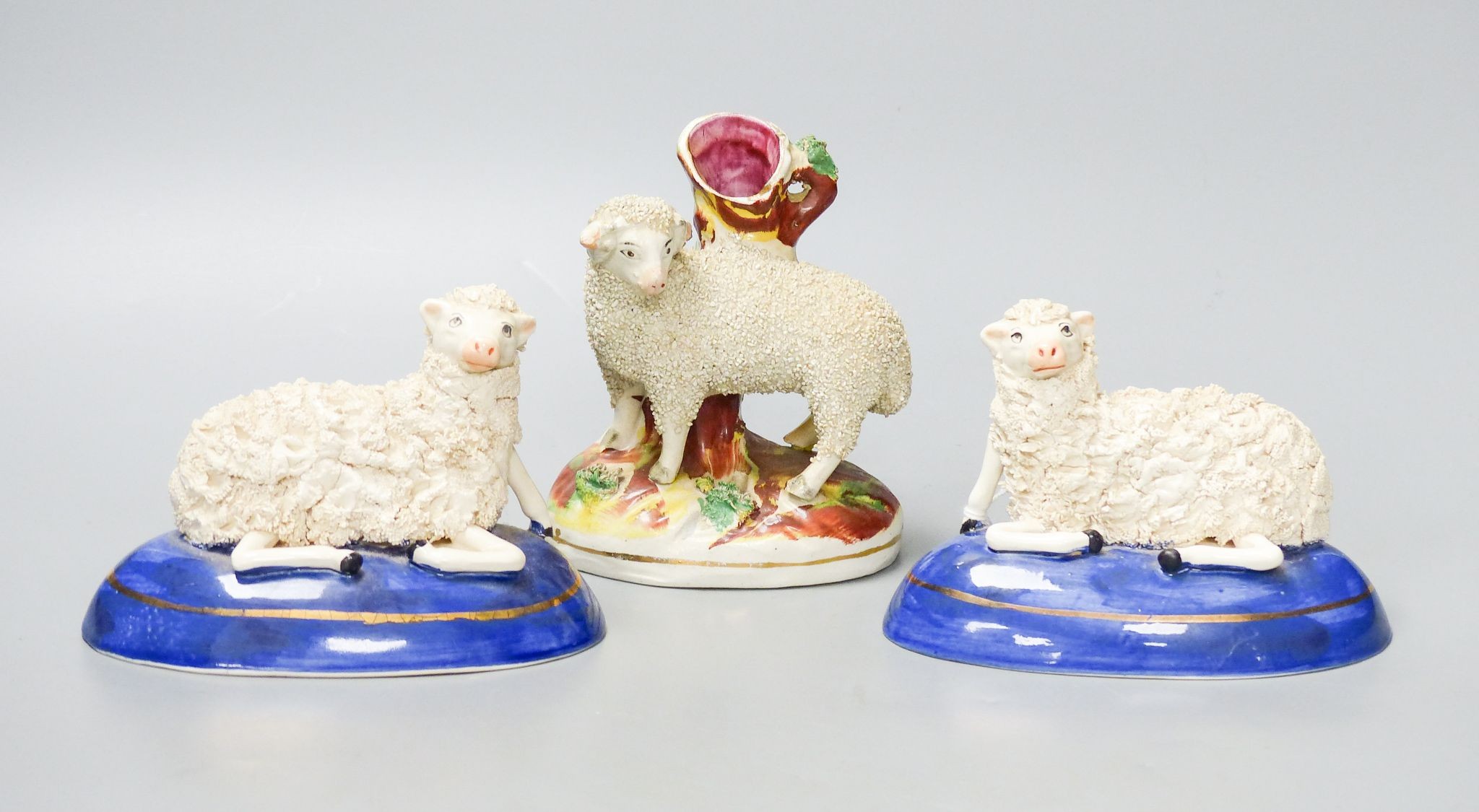 A pair of Staffordshire pottery figures of recumbent sheep, and a similar spell vase, tallest 12.5 cm